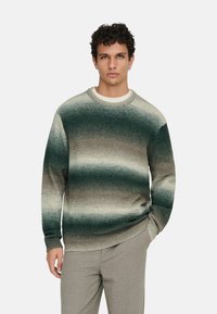 Pull en maille avec un dégradé horizontal de tons verts et beiges. Il présente un col rond, des poignets côtelés et une texture douce.