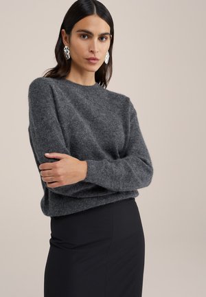 Gray wool sweater with a round neckline and long sleeves, featuring a soft texture and a relaxed fit, paired with a black skirt.