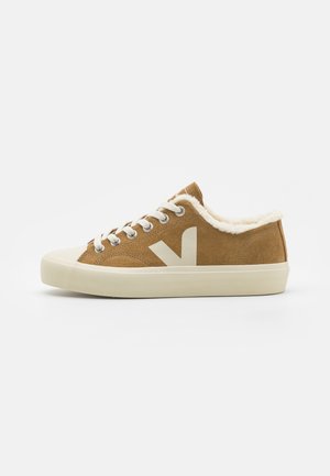 Sneaker in suede marrone con suola in gomma crema, fodera soffice e un grande logo bianco sul lato. Presenta lacci bianchi e occhielli metallici.