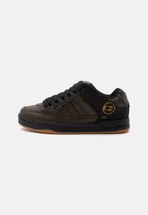 Baskets basses en cuir noir et marron avec lacets noirs, col rembourré et semelle en caoutchouc beige, avec les logos de la marque Globe sur le côté.