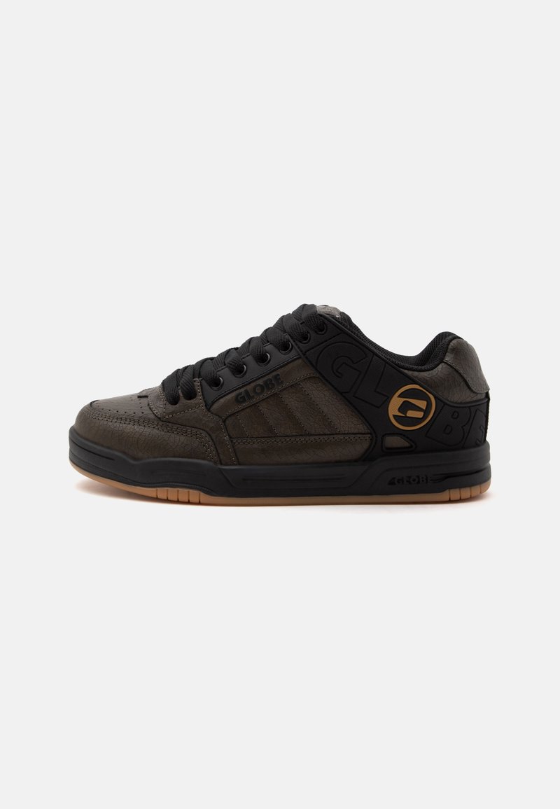 Baskets basses en cuir noir et marron avec lacets noirs, col rembourré et semelle en caoutchouc beige, avec les logos de la marque Globe sur le côté.