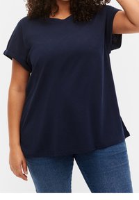 Navyblå bomullstop med kort ärm som har rund halsringning, uppvikta ärmar och en avslappnad passform, kombinerad med denimjeans.