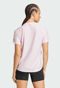Camiseta corta de manga corta en color rosa con un ajuste relajado y cuello redondo, hecha de un material transpirable. La parte trasera muestra una textura suave y sin patrones.