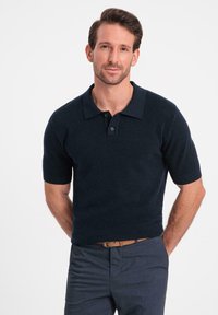 Marine polo skjorte med korte ærmer, tekstureret strikket stof og en klassisk krave. Har en tre-knap lukning og en tætsiddende design.