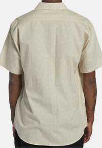 Korte mouwen shirt in lichtbeige met een gestructureerd ruitpatroon, voorzien van een kraag en een rechte zoom. De stof heeft een zachte, gladde oppervlakte.
