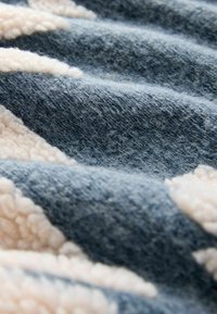 Soft, textured blanket with alternating blue and cream colors, featuring a mix of woven and fluffy fabric patterns.