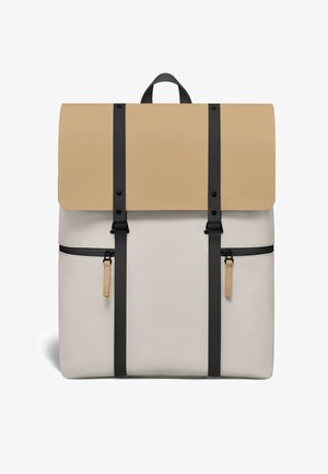 Beżowo-kremowy plecak Gaston Luga z czarnymi pionowymi paskami, dwoma przednimi kieszeniami na zamek oraz górnym uchwytem.