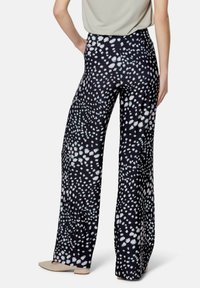 Black wide-leg pants featuring a white speckled pattern, made from a lightweight fabric with a smooth texture, shown from the back.