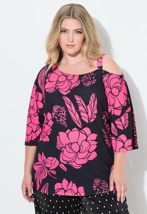 Schwarzes Oberteil mit pinkfarbigem Blumenmuster, schulterfreiem Design und lockerer Passform. Kurze Ärmel und weicher Stoff, ergänzt durch Punkte-Hosen.