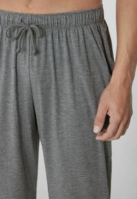 Grau gefärbte Jogginghose aus weichem, leichtem Stoff. Sie verfügt über einen elastischen Bund und einen lockeren Schnitt mit zarter Textur.