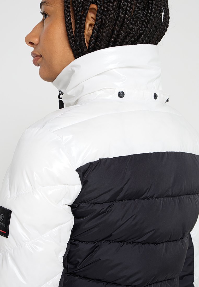  gepolsterte Jacke mit einer weißen glänzenden Vorderseite und einem schwarzen strukturierten Rücken, hohem Kragen, Druckknöpfen und einem Logopatch an der Seite.