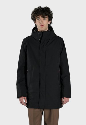 Chaqueta negra impermeable con capucha, que cuenta con un cierre de cremallera y dos bolsillos laterales. Textura de tela suave, diseño minimalista, corte regular.