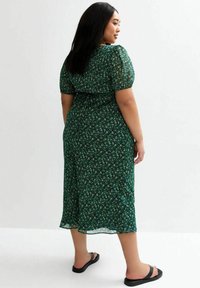 Groene bloemen midi-jurk met pofmouwen, tailleaccent, lichtgewicht stof en een vloeiende silhouet. Draag met zwarte slippers.