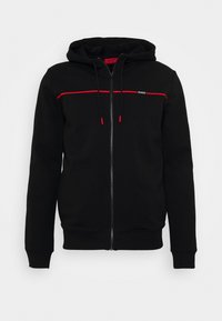Sudadera negra con cremallera y una franja de acento roja en el pecho, que cuenta con capucha, cordones y puños y dobladillo acanalados. Textura de tela suave.