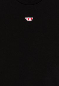 Svart tyg med litet rött och vitt broderat logotyp centrerat nära toppen.