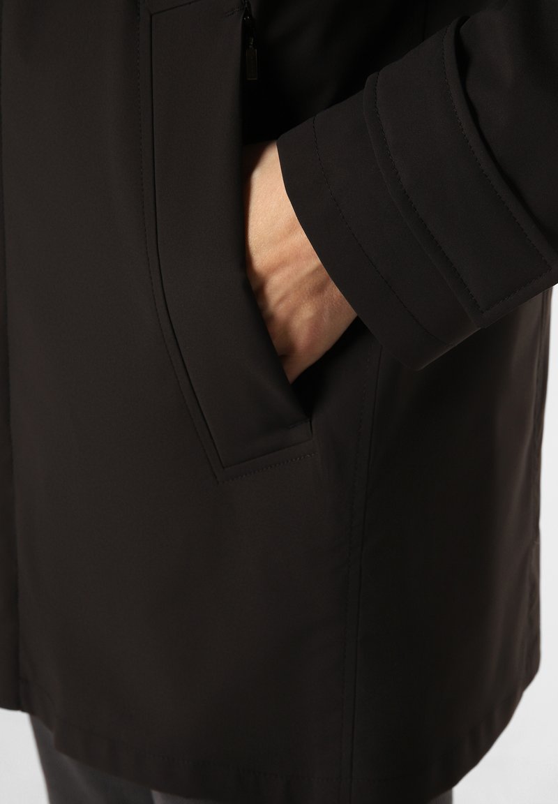 Czarna kurtka o eleganckim designie, z boczną kieszenią, gładkiego materiału i przeszywanymi detalami na mankietach.