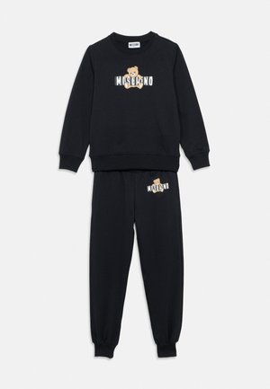 Completo nero composto da felpa a maniche lunghe e pantaloni con stampa di orsetto e logo Moschino sul petto e sulla parte superiore della gamba sinistra.