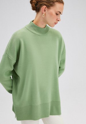 Lichtgroene gebreide trui met een hoge hals, oversized pasvorm, geribbelde zoom en verlaagde schouders. Glad textuur, modern ontwerp en geen zichtbare patronen.