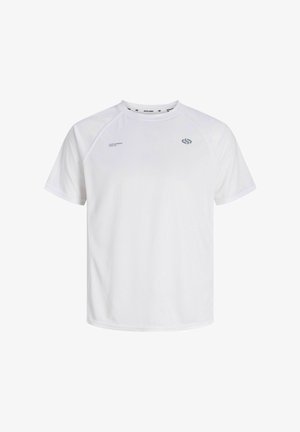 Garçon portant une casquette blanche, une veste et un short bleu marine, un t-shirt blanc, des chaussettes rayées et des baskets blanches, debout devant un fond uni en souriant.