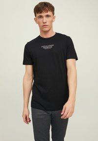 Juodas medvilninis trumpomis rankovėmis marškinėliai su baltu "Jack & Jones Premium" logotipu, centruotu ant krūtinės, su klasikinio apvalaus kaklo iškirpte.