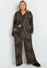 Leopardmönstrad loungewear-set som har en svart bas med tanfläckar, långärmad knapp-up-top, vida byxor och mjuk tygtextur.