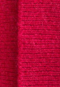 Knit fabric in vibrant red with a textured surface and visible fibers. Features a consistent pattern and slight variations in thickness.