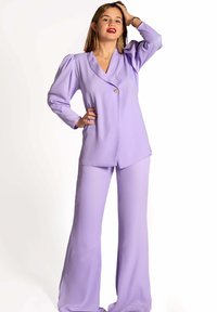 Conjunto de dos piezas en lavanda hecho de un tejido suave. Presenta una americana con un escote en V profundo, mangas abullonadas y pantalones acampanados. Detalle de botón dorado.