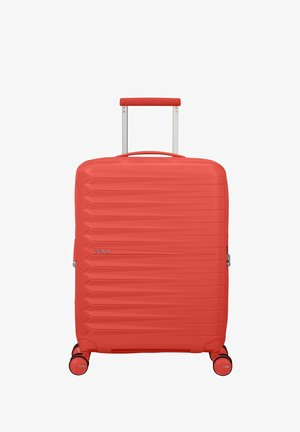 Valise rigide rouge avec poignée rétractable et quatre roues pivotantes, présentant des rainures horizontales et une serrure à glissière latérale.