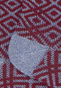 Maglione a maglia in bordeaux e blu con un motivo geometrico; tessuto testurizzato, con un distintivo dettaglio di polsino blu su un lato.