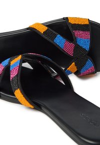 Sandalia negra con coloridos bordados en naranja, rosa, azul y negro en las correas, con un diseño de suela plana y suave.