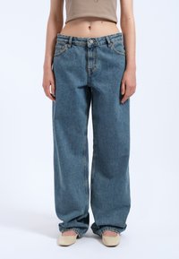 Světle modré, volné džíny z denimu s vysokým pasem, zapínání na knoflík a zip, design s pěti kapsami a třepeným lemem na kotnících.