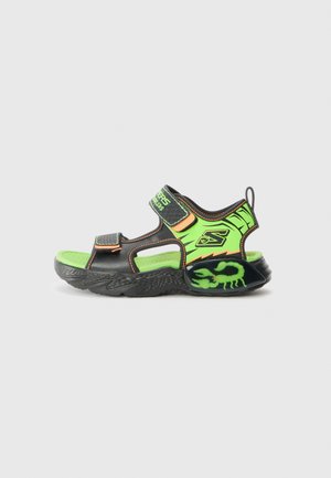 Black and neon green sandal with adjustable straps, textured rubber sole, and a scorpion graphic on the heel. Lightweight design for comfort.