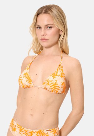 Mujer con cabello rubio que lleva un top de bikini halter con estampado floral en naranja y rosa claro sobre un fondo liso.