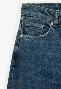 Vaqueros de mezclilla en azul oscuro, con un diseño clásico de cinco bolsillos, costuras en contraste y un pequeño bolsillo frontal cerca de la cinturilla.