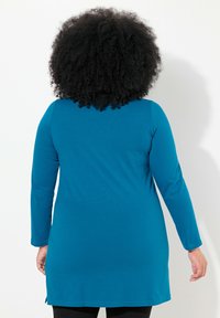 Tunic a maniche lunghe in tessuto teal, con scollo rotondo e spacchi laterali all'orlo, progettata per una vestibilità ampia.