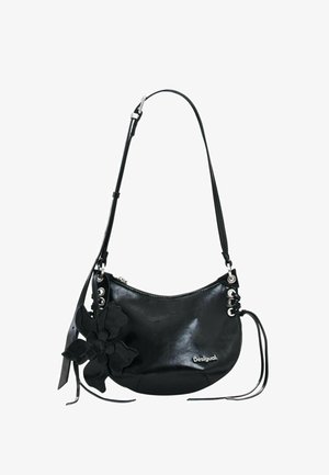 Bolso de hombro de cuero negro en forma de media luna con correa ajustable, decoración floral, ojales de metal y logo "Desigual" en la parte delantera.
