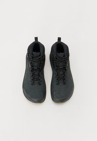 Höga svarta sneakers med en slät syntetisk ovandel, strukturerade detaljer, platta snören och en dragflik vid kragen. Vibram-logotypen syns på sulan.