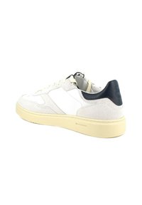 Sneaker in suede bianco con suola in gomma crema; presenta un pannello in pelle bianca liscia e un accento in pelle blu navy sul tallone.