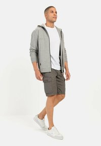 Grå zip-up hoodie med en hvid T-shirt under, parret med grå cargo shorts og hvide sneakers, har praktiske lommer og en afslappet pasform.