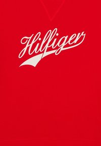 Felpa in cotone rossa con logo "Hilfiger" bianco in un carattere corsivo stilizzato, con scollatura a V e orlo a coste per una maggiore texture.