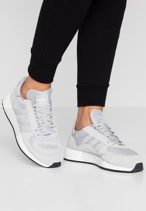Sneaker sportive grigio chiaro con tomaia in mesh e suede, design a tre strisce, suola flessibile e intersuola bianca texturizzata. Accenti in lilla.