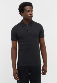 Czarna koszulka polo z kołnierzykiem, krótkimi rękawami, zapięciem na trzy guziki i małym logo na klatce piersiowej. Wykonana z gładkiego, fakturowanego materiału.