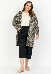 Kimono stil kardigan s uzorkom tigrove kože, s crnim skraćenim hlačama koje imaju bočne džepove i gumbe kao detalje, u kombinaciji s bež balerinama.