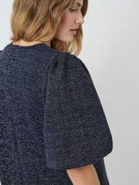Navyblaues, strukturiertes Kleid mit kurzen Puffärmeln, das ein dezentes Muster und einen runden Ausschnitt aufweist. Weiches Material mit einem leichten Schimmer.