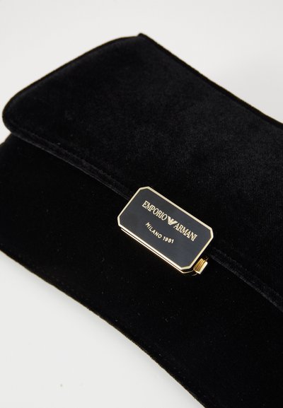 Svart fløyels Emporio Armani-kortholder med gullfarget logo-plate som leser "EMPORIO ARMANI MILANO 1981" på frontklaffen.