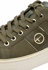 Sneaker verde oliva in pelle martellata, con occhielli dorati e lacci piatti. Presenta una punta arrotondata e una suola in gomma con un motivo sottile.