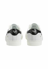 Weiße Sneakers mit schwarzen Absatzakzenten, flachen Schnürsenkeln, strukturierten Gummisohlen und hervorgehobener Markenprägung auf der Rückseite. Glattes synthetisches Material.