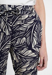 Námořnické kalhoty z látky s bílým vzorem listů, se strečovým pasem se šňůrkou a bočními kapsami. Hladká textura.