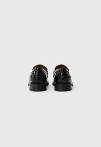 Sorte lær loafers med en glossy krokodillepreget tekstur, rund tå og lav hæl, med et elegant design og minimal søm.