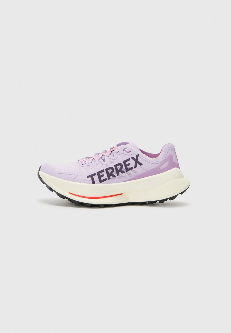 Ljubičaste trkačke tenisice s prozračnim mrežastim gornjim dijelom, istaknutim "TERREX" logotipom, bijelim srednjim dijelom i crnim gumеним potplatom s crvenim akcentom.